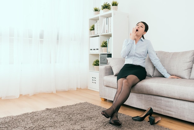 elle a sommeil assise sur le canapé du salon à la maison après le travail