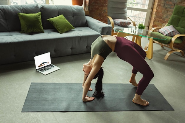 Élongation. Belle jeune femme sportive pratiquant les asanas du yoga comme professionnelle à la maison.