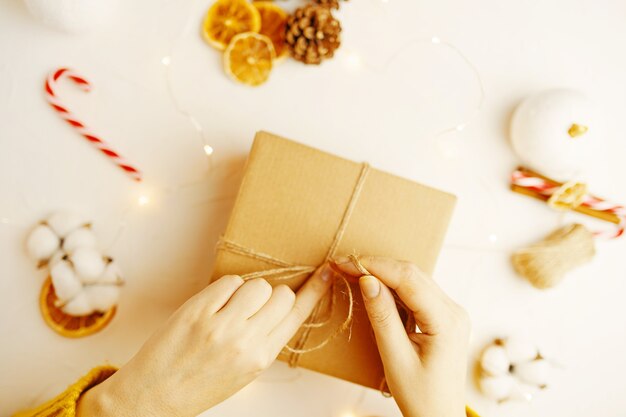 Emballage de boîte-cadeau de noël cônes de sapin, tranches d'orange sèches et autres décorations sur table girl in s ...