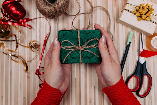 Emballage cadeau. Femme emballe des cadeaux de vacances à la maison sur une table en bois.