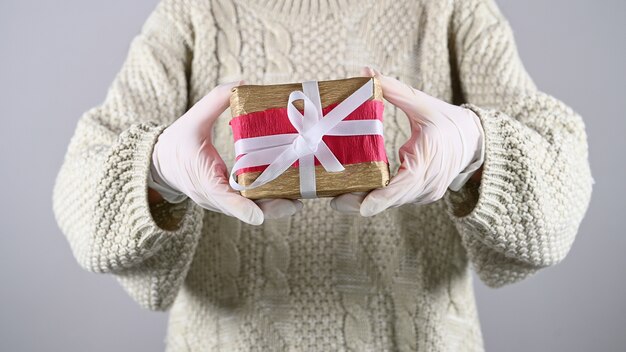 Emballage cadeau avec des gants en caoutchouc. Fille tenant un emballage cadeau dans des gants en caoutchouc.