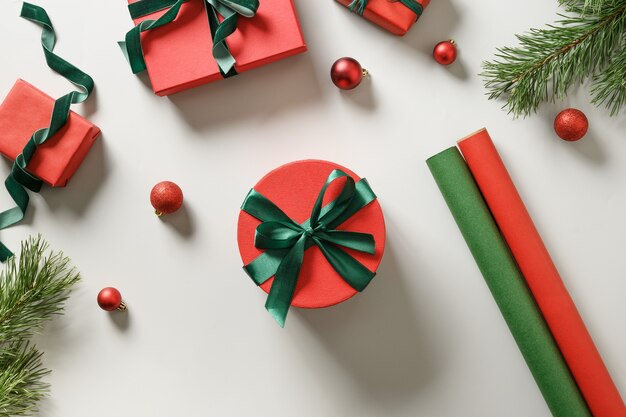 Emballage des cadeaux de Noël dans du papier rouge et vert sur fond gris.