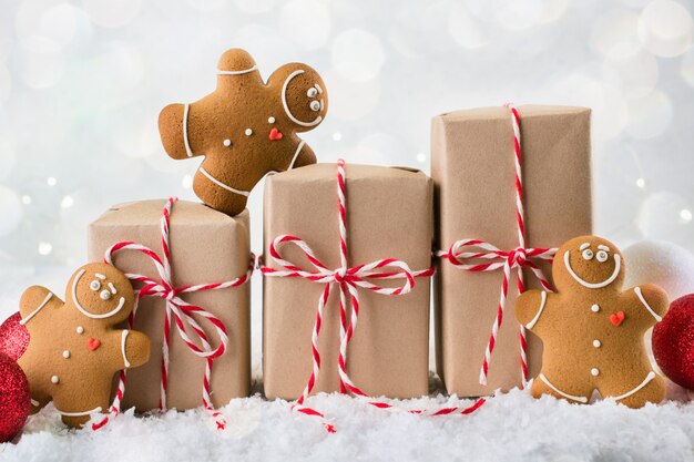 Emballage de cadeaux de Noël. Trois coffrets cadeaux de Noël enveloppés dans du papier kraft attaché avec de la ficelle rouge et blanche et trois biscuits de pain d'épice souriant