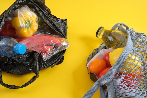 Emballage jetable en plastique versus réutilisable, pas de concept en plastique, sac en filet et sac d'épicerie en plastique sur fond jaune espace de copie