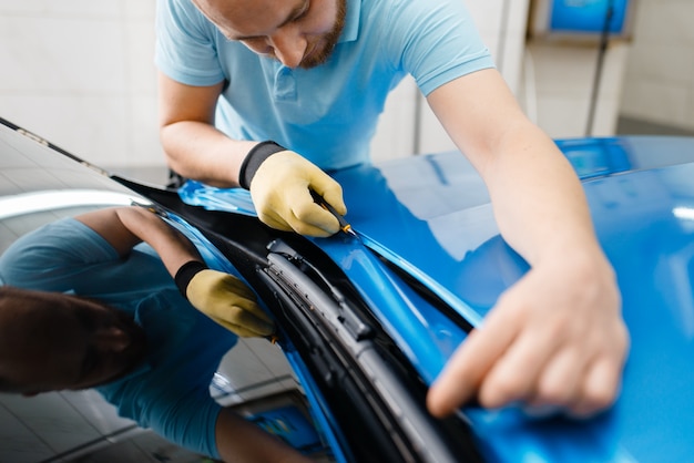 Emballage de voiture, l'homme coupe une feuille ou un film protecteur