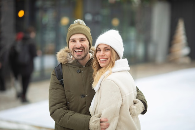 Embrassant le couple regardant la caméra avec des sourires dans le parc d'hiver.