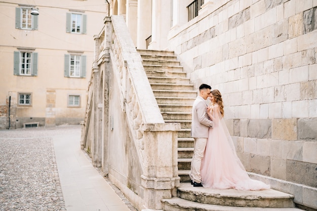 Embrassant les jeunes mariés debout sur les marches d'un ancien bâtiment à Bergame, Italie