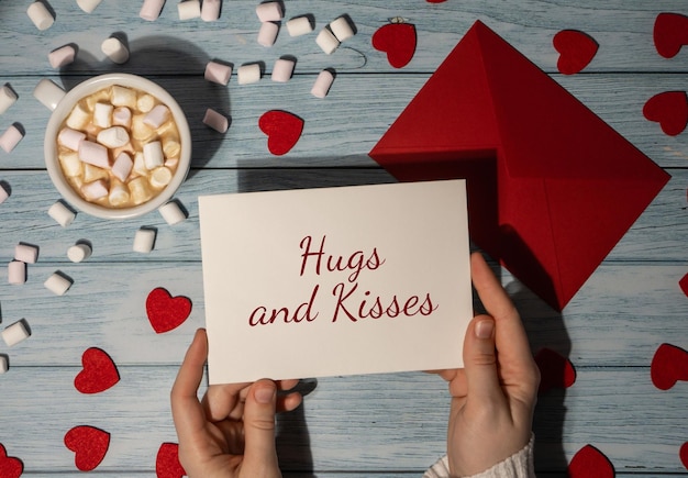 Photo embrassements et baisers texte sur la carte de la saint-valentin mains féminines tenant une carte de la saint-valentin enveloppe rouge avec blanc