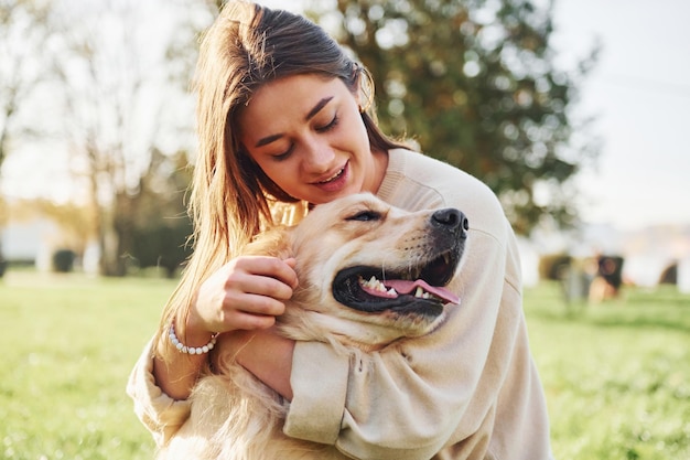 Embrasser l'animal de compagnie Jeune femme se promener avec Golden Retriever dans le parc