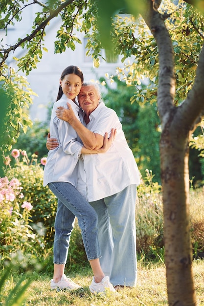 Embrasser et poser pour un appareil photo Jeune femme est avec sa mère âgée est dans le jardin