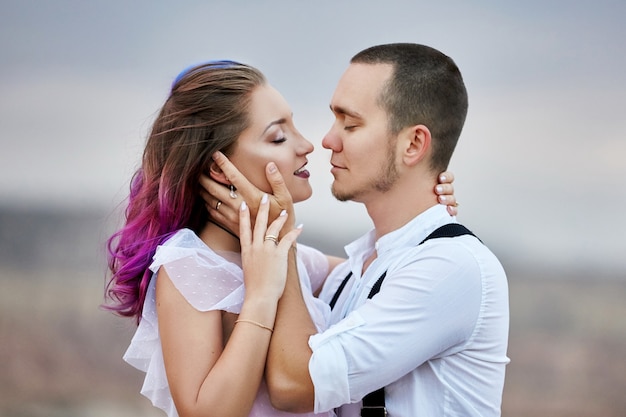 Embrassez et embrassez un couple amoureux un matin de printemps dans la nature. La Saint-Valentin, une relation étroite entre un homme et une femme. Homme embrassant une fille aux cheveux de couleur vive, coloration créative