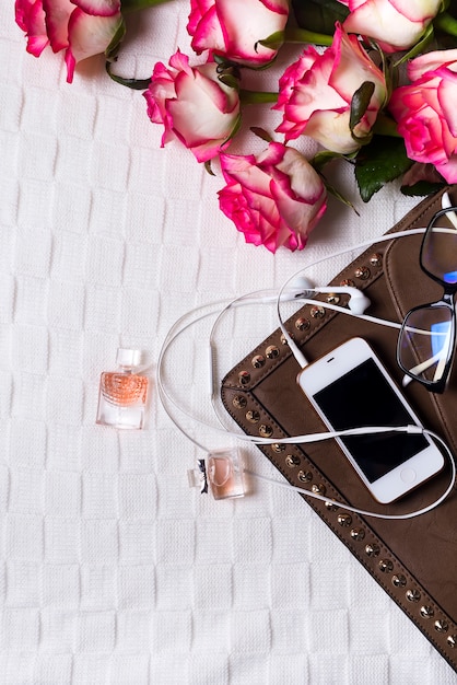 Embrayage femme avec téléphone, casque et bouteilles de parfum avec des fleurs