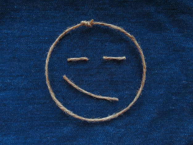 Photo emoji. émoticône souriante en ficelle sur denim bleu. fermer