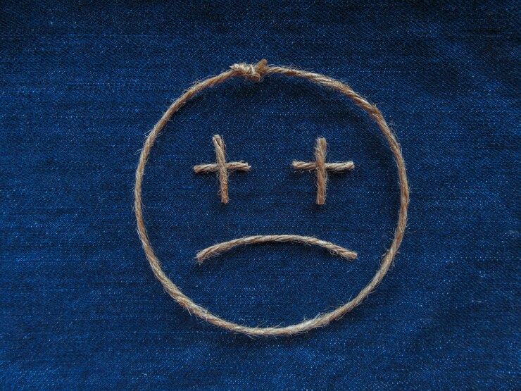 Photo emoji. smiley triste en ficelle sur denim bleu. fermer
