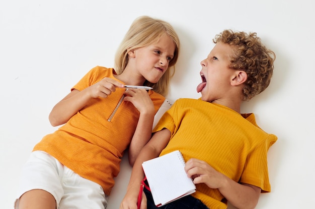 Émotions de garçon et de fille rassemblant le bloc-notes et les crayons fond isolé inchangé