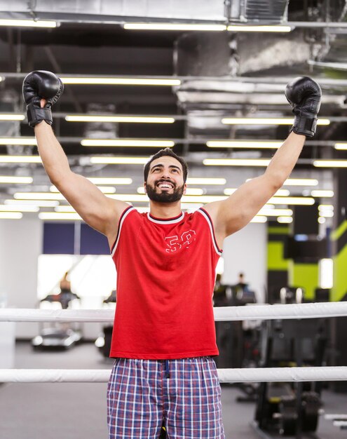 Photo Émotions de victoire d'un beau boxeur barbu avec des gants noirs sur le ring