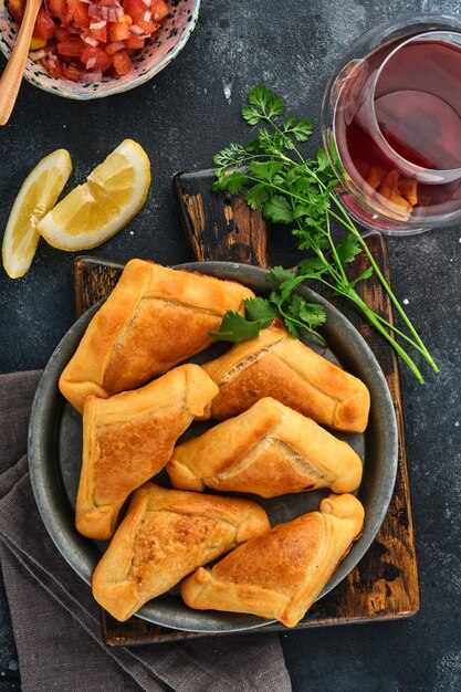 Empanadas frites avec coriandre, viande, oeuf, tomate et sauce chili sur fond noir. Plat typique chilien. Concept de la fête de l'indépendance de l'Amérique latine et du Chili.