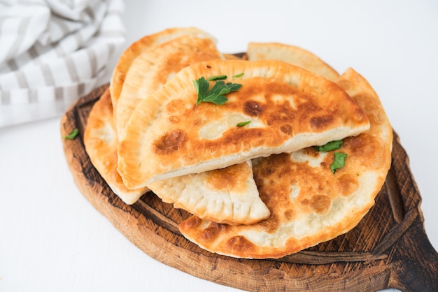 Empanadas frites maison au porc, chebureks aux champignons sur une planche de bois, gros plan