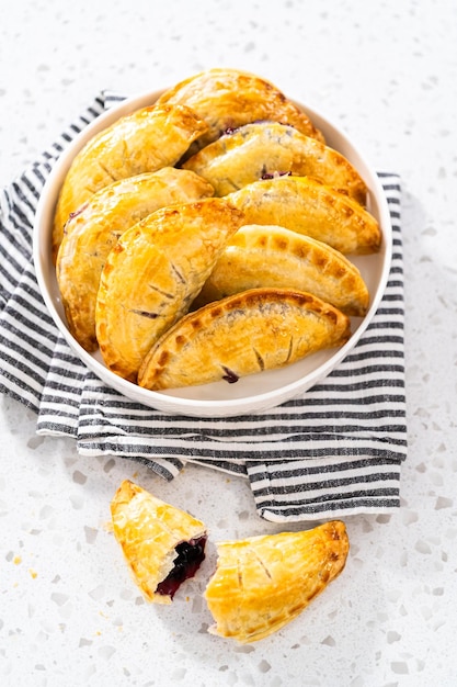 Empanadas sucrées fraîchement cuites au four avec des myrtilles sur le comptoir de la cuisine