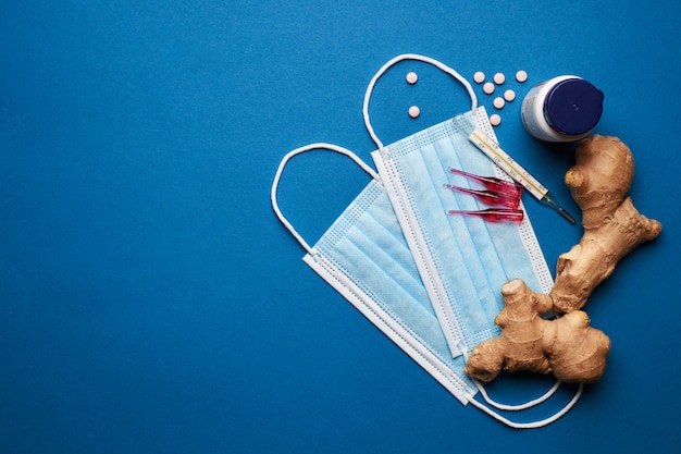 Empêchez les coronavirus. Masque médical, thermomètre, vitamines, seringue sur fond bleu.