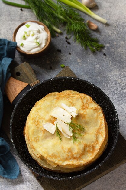 Empiler des crêpes de pommes de terre non sucrées servies avec une sauce à la crème à l'ail sur fond de pierre grise