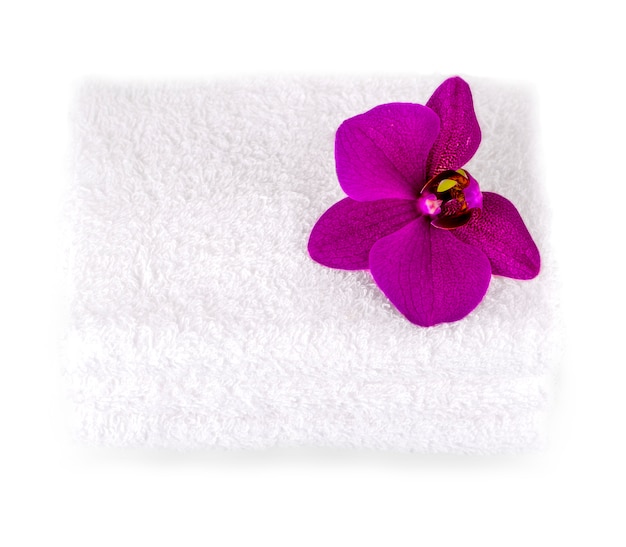 Empilez des serviettes blanches pour spa avec une fleur d’orchidée pourpre.