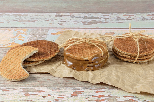 Empilez Les Stroopwafels Sur Du Papier Brun, à Côté D'un Autre Biscuit Avec Une Bouchée (vue Latérale).