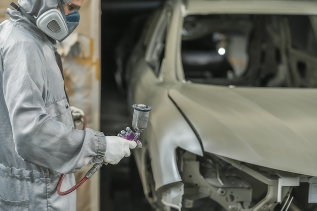 Un employé de l'atelier de peinture prépare la carrosserie pour la peinture