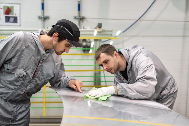 Photo un employé de l'atelier de peinture de l'usine automobile organise une formation sur le dépoussiérage avec un chiffon de cire spécial