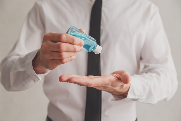 Employé de bureau à l'aide d'un tube de distributeur de gel désinfectant pour les mains. Concept antiseptique, hygiène et soins de santé