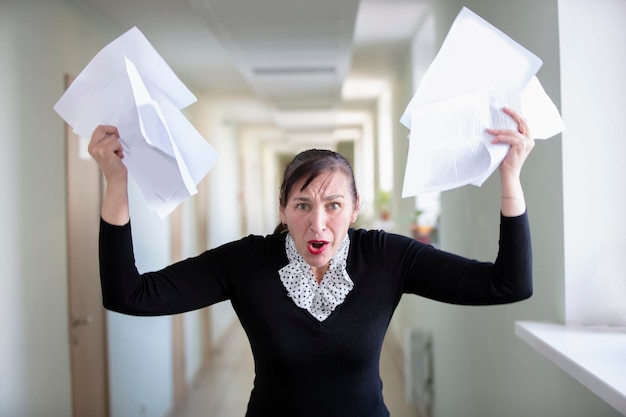 Employé de bureau dans le stress Une femme inégale éparpille du papier