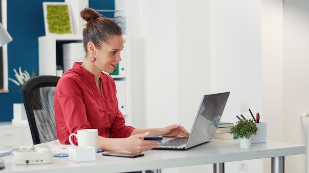 Employé de bureau effectuant un paiement par carte de crédit sur un ordinateur portable, faisant des achats en ligne pour la croissance de l'entreprise et le développement de l'entreprise. Femme achetant dans un magasin de détail discount, achat de commerce électronique.