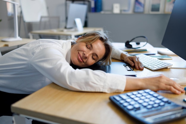 Employé de bureau féminin avec les yeux fermés faisant la sieste sur le lieu de travail