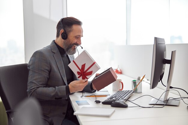 Employé de bureau heureux tient un cadeau et souriant