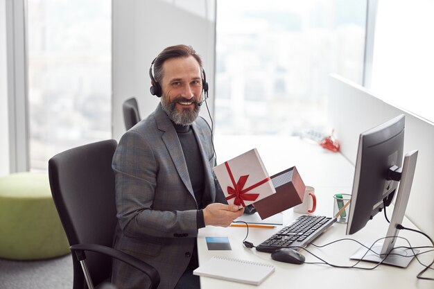 Employé de bureau heureux tient un cadeau et souriant