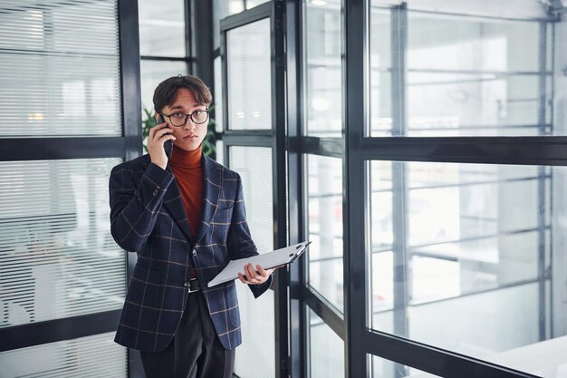 Employé de bureau en lunettes et en vêtements formels marchant à l'intérieur.