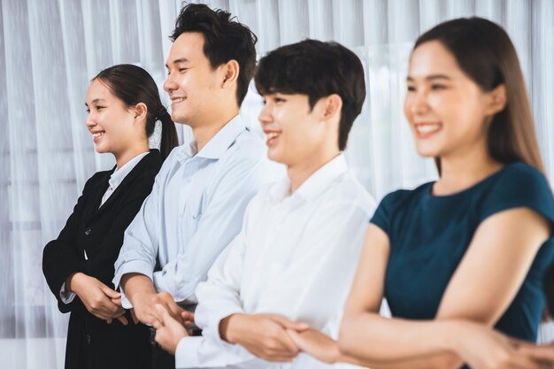 Un employé de bureau multiracial se tient la main dans une ligne pour promouvoir la synergie et la concorde.