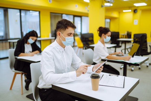 Employé de bureau portant un masque facial pour la distanciation sociale pour la prévention des virus lors de l'utilisation d'un ordinateur portable.