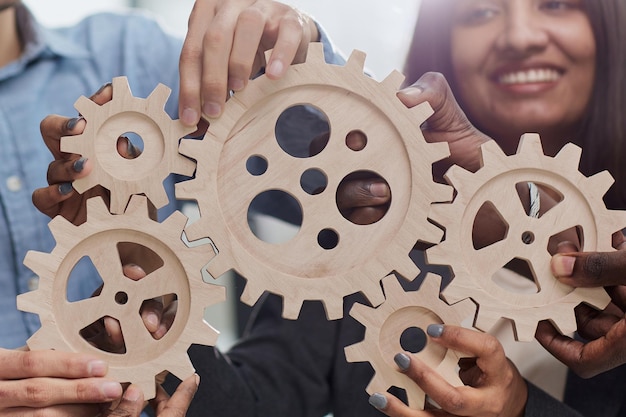 Photo employé de bureau tenant une roue dentée comme unité et travail d'équipe dans le concept de lieu de travail d'entreprise