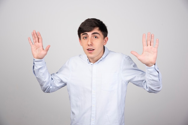 employé de bureau en tenue de soirée montrant un geste d'arrêt sur un mur gris.