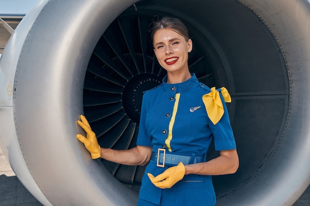 employé de compagnie aérienne souriant et élégant s'appuyant d'une main sur le moteur de l'avion