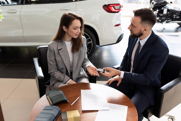 Employé d'un concessionnaire automobile remettant les clés d'une nouvelle voiture à une jeune femme