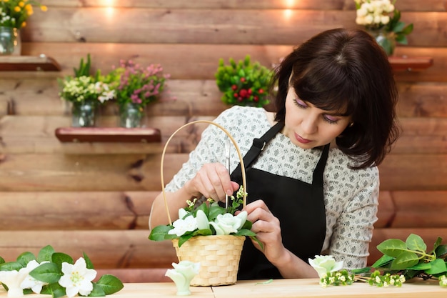 Un employé du magasin recueille un bouquet de fleurs et du savon dans un panier