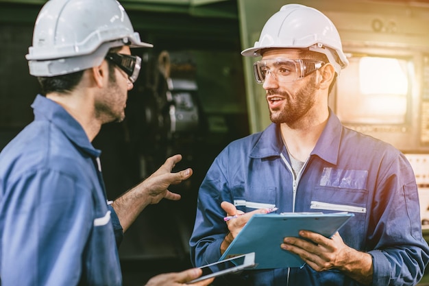 Employé du personnel ingénieur parler discussion aider l'équipe de travail avec l'industrie de la machine métallurgique en usine