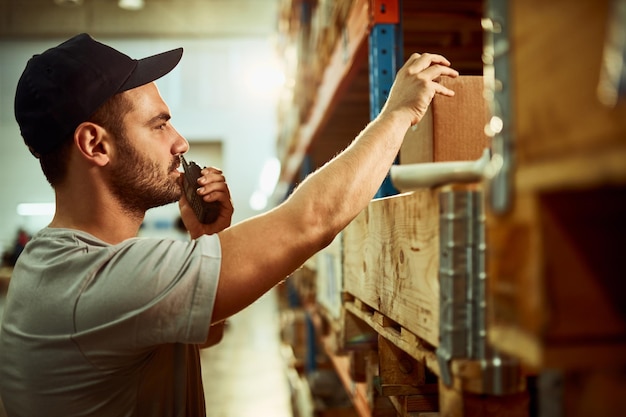 Employé d'entrepôt communiquant par talkie-walkie dans un compartiment de stockage industriel