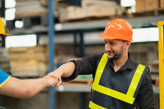 Employé d'entrepôt industriel ou ingénieur dans la poignée de main de la suite de sécurité célébrer un engagement réussi ou un accord Chaîne d'approvisionnement logistique et entreprise d'entrepôtUnité de travail d'équipe sous le concept de vue