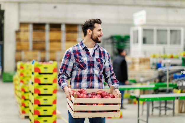 Un employé d'entrepôt transporte une caisse avec des pommes et fait une livraison