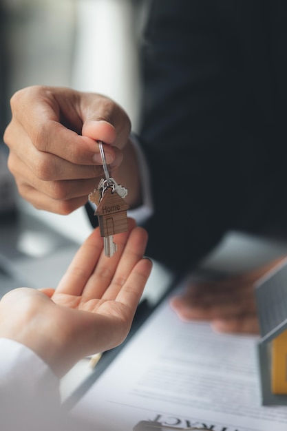 Un employé de l'entreprise de location de maisons remet les clés de la maison à un client qui a accepté de signer un contrat de location expliquant les détails et les conditions de la location Idées de location de maison et d'immobilier