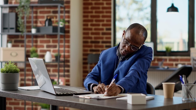 Employé de l'entreprise parlant sur un téléphone portable au bureau, composant le numéro pour avoir une conversation à distance. Homme d'affaires utilisant un smartphone pour une discussion de télétravail, une conversation téléphonique. Prise de vue au trépied.