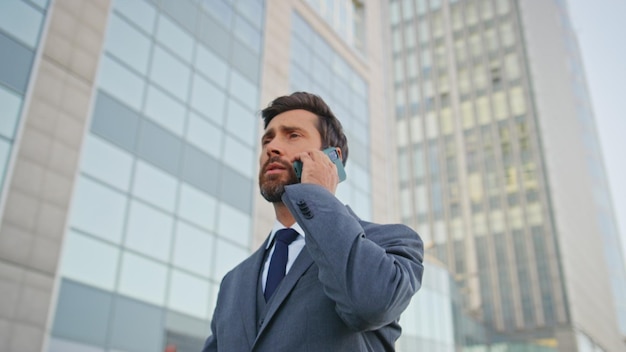 Un employé de l'entreprise parle au téléphone portable en marchant dans un quartier d'affaires urbain.